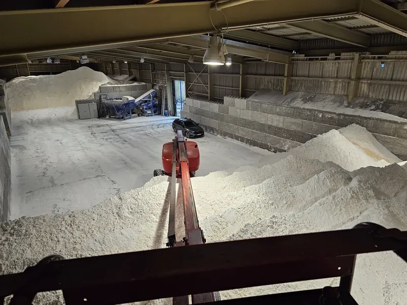 Bird's-eye view of a salt warehouse with conveyor system and bulk piles, captured from the survey lift platform during a Sachtleben bulk-inventory campaign