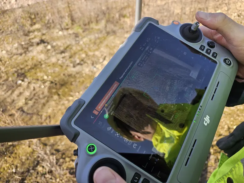 DJI flight controller showing live drone view during a stockpile aerial survey — pilot's perspective during the mission